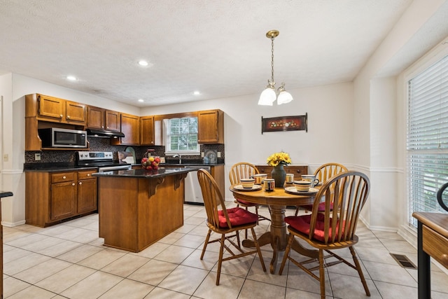217 Fox Hunt Ln, Lebanon, TN 37087 - kitchen with appliances with stainless steel finishes, tasteful backsplash, a kitchen island, dark countertops, and brown cabinetry