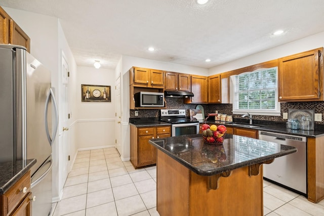 217 Fox Hunt Ln, Lebanon, TN 37087 - kitchen with appliances with stainless steel finishes, under cabinet range hood, light tile patterned flooring, backsplash, and brown cabinetry