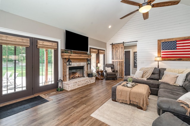 398 Beasleys Bend Rd, Lebanon, TN 37087 - living room with a barn door, wood finished floors, a ceiling fan, high vaulted ceiling, and wooden walls
