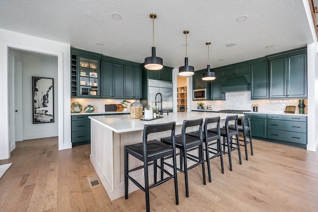 1224 Ben Forkum Dr, Lebanon, TN 37087 - kitchen featuring built in appliances, premium range hood, light wood finished floors, light countertops, and decorative backsplash