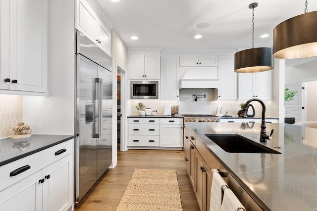 1224 Ben Forkum Dr, Lebanon, TN 37087 - kitchen featuring built in appliances, light wood finished floors, tasteful backsplash, decorative light fixtures, and white cabinetry