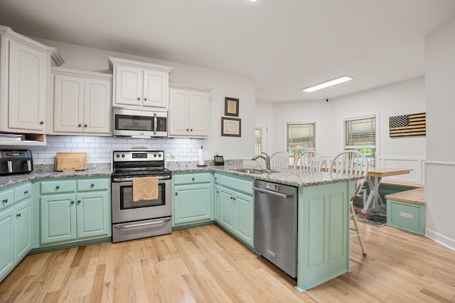 29 Harbor Pt, Lebanon, TN 37087 - kitchen with appliances with stainless steel finishes, a peninsula, light wood finished floors, and white cabinets