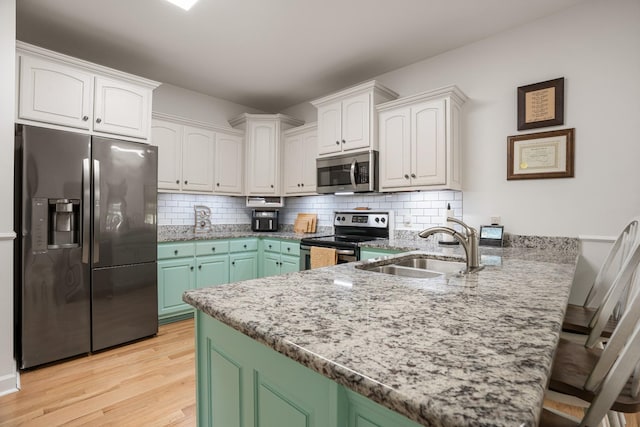 29 Harbor Pt, Lebanon, TN 37087 - kitchen with appliances with stainless steel finishes, a peninsula, white cabinets, light stone counters, and backsplash