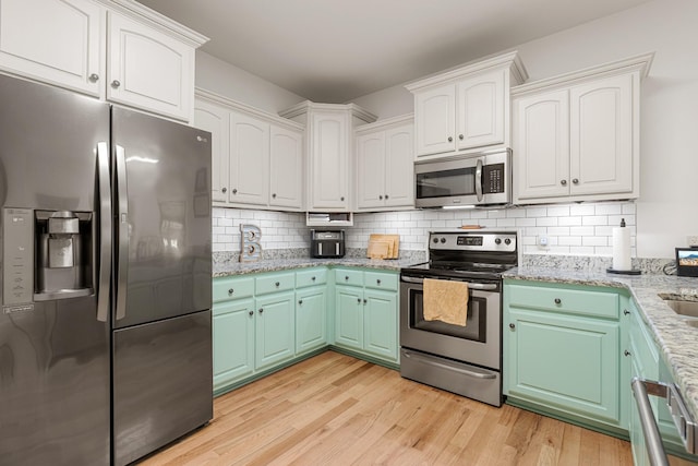 29 Harbor Pt, Lebanon, TN 37087 - kitchen with appliances with stainless steel finishes, light wood finished floors, backsplash, light stone countertops, and white cabinets