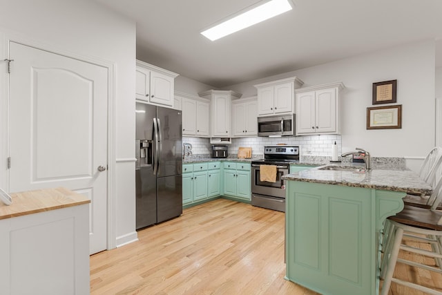 29 Harbor Pt, Lebanon, TN 37087 - kitchen with appliances with stainless steel finishes, a peninsula, white cabinetry, and light wood-style floors