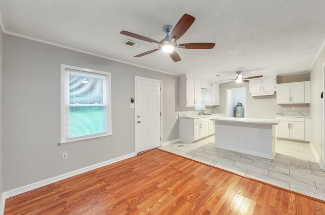 274 Spring Hill Rd, Stanton, TN 38069 - kitchen with ceiling fan, ornamental molding, white cabinets, a center island, and a textured ceiling