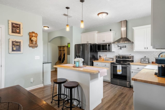 2210 Indian Mound Rd, Woodlawn, TN 37191 - kitchen with stainless steel appliances, butcher block counters, wall chimney exhaust hood, arched walkways, and a textured ceiling