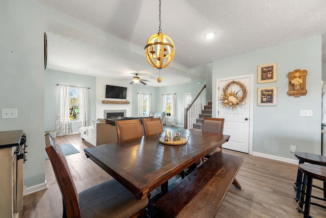 2210 Indian Mound Rd, Woodlawn, TN 37191 - dining space with wood finished floors, a textured ceiling, a fireplace, stairs, and ceiling fan
