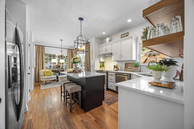 7767 Lynnle Way, Hixson, TN 37343 - kitchen with stainless steel appliances, a kitchen island, light wood finished floors, white cabinets, and a kitchen bar