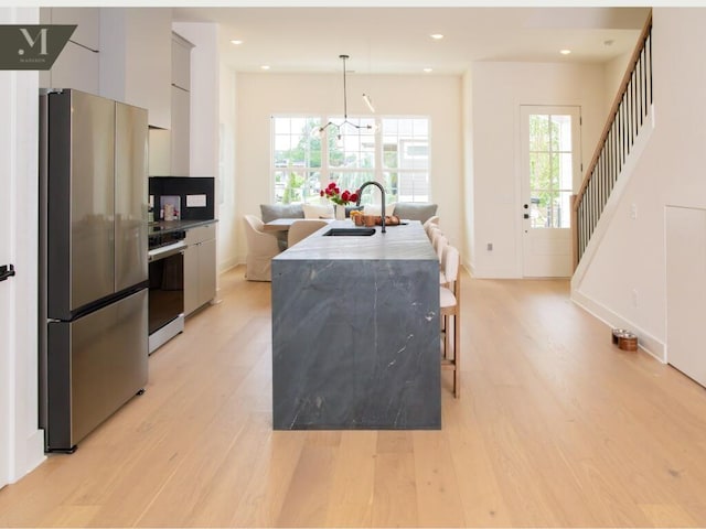 1572 Madison St, Chattanooga, TN 37408 - kitchen featuring appliances with stainless steel finishes, modern cabinets, light wood-style flooring, an island with sink, and pendant lighting