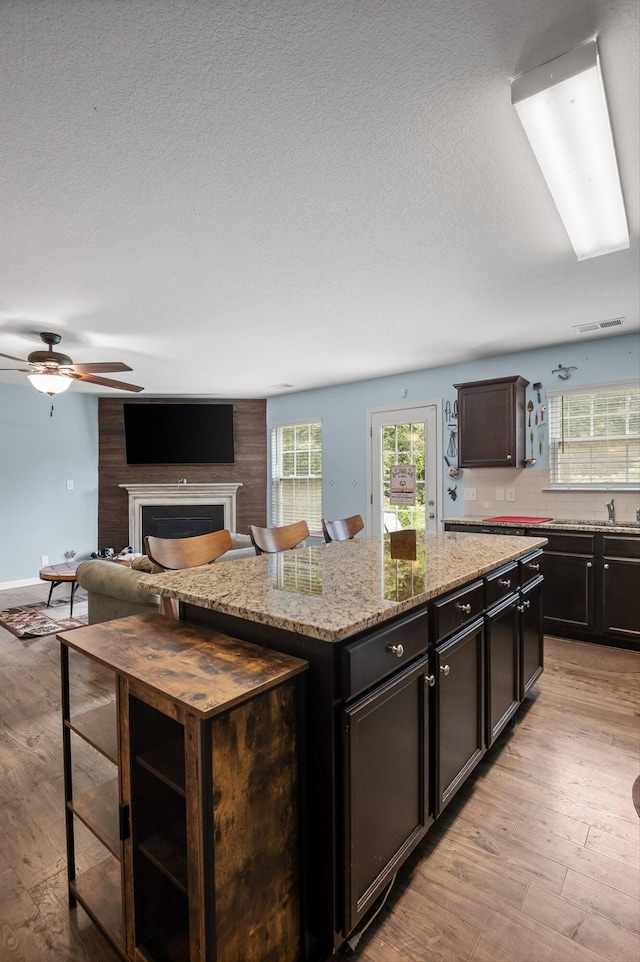 15252 Foamflower Ln, Sale Creek, TN 37373 - kitchen with light wood-style flooring, a kitchen island, ceiling fan, light stone countertops, and a textured ceiling