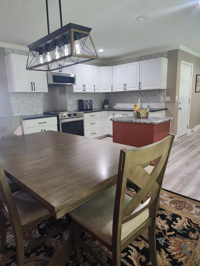 119 Horn Ave, Loretto, TN 38469 - kitchen featuring stainless steel appliances, ornamental molding, decorative backsplash, white cabinetry, and pendant lighting