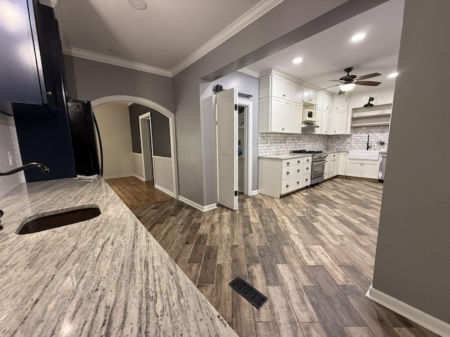 236 N Carolina Ave, Sewanee, TN 37375 - kitchen featuring arched walkways, stainless steel appliances, a ceiling fan, open shelves, and dark wood-type flooring