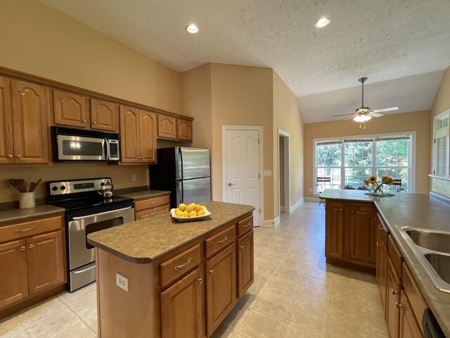 2714 Maylon Dr, Murfreesboro, TN 37128 - kitchen with stainless steel appliances, vaulted ceiling, brown cabinets, a kitchen island, and a textured ceiling