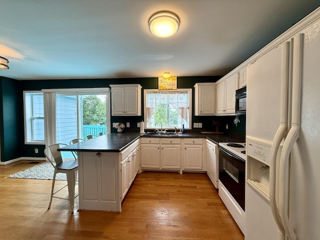 465 Turtle Point Ln, Waverly, TN 37185 - kitchen with white appliances, a peninsula, dark countertops, a kitchen bar, and white cabinets