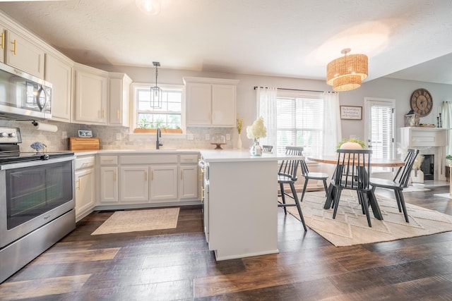 108 Larry Joe Pl, Portland, TN 37148 - kitchen with stainless steel appliances, dark wood-style floors, light countertops, a breakfast bar, and decorative backsplash