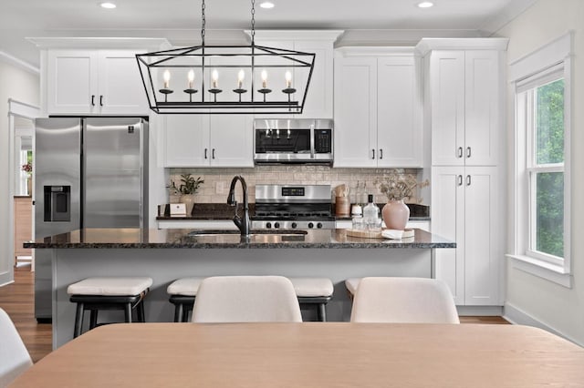 3767 Lee Pike, Soddy Daisy, TN 37379 - kitchen with appliances with stainless steel finishes, backsplash, a kitchen island with sink, white cabinetry, and ornamental molding
