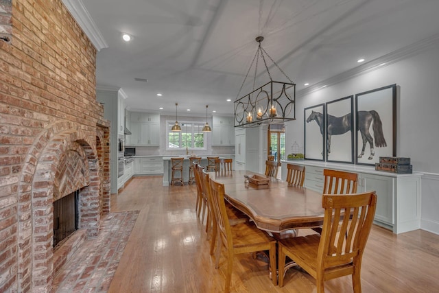 2485 Old Natchez Trce, Franklin, TN 37069 - dining area featuring crown molding, a fireplace, light wood-style flooring, recessed lighting, and a chandelier