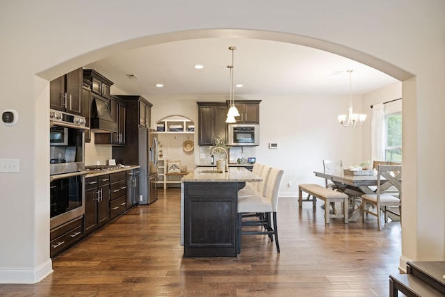 222 Fowler Cir, Franklin, TN 37064 - kitchen with stainless steel appliances, premium range hood, tasteful backsplash, light stone counters, and dark brown cabinets