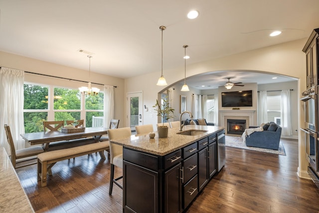 222 Fowler Cir, Franklin, TN 37064 - kitchen with a glass covered fireplace, a kitchen bar, arched walkways, ceiling fan, and light stone counters