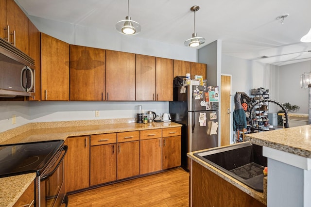 863 Flynn St Unit 302, Chattanooga, TN 37403 - kitchen with stainless steel appliances, brown cabinets, light wood finished floors, and hanging light fixtures