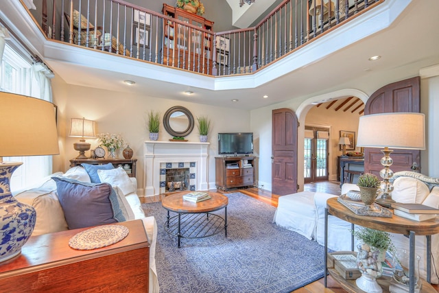 9710 Concord Rd, Brentwood, TN 37027 - living room featuring arched walkways, a high ceiling, wood finished floors, a tile fireplace, and recessed lighting