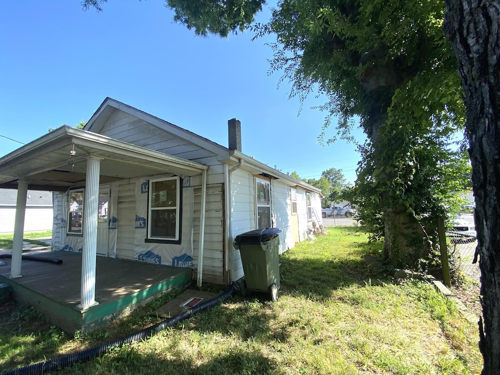 807 Maple Ct, Hopkinsville, KY 42240 - view of side of home with a chimney, a lawn, and covered porch