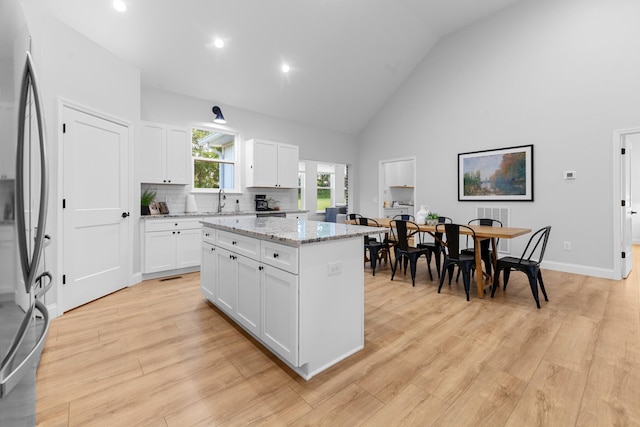 5283 Eagleville Pike, Eagleville, TN 37060 - kitchen featuring stainless steel refrigerator, a kitchen island, light stone countertops, white cabinets, and high vaulted ceiling
