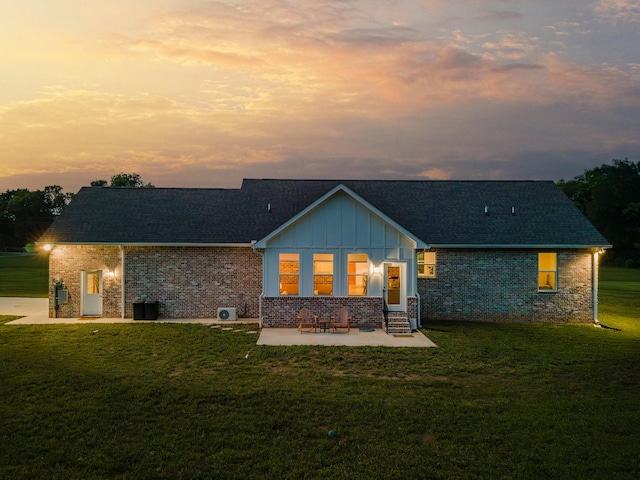 5283 Eagleville Pike, Eagleville, TN 37060 - back of house at dusk featuring entry steps, a patio area, a yard, brick siding, and board and batten siding