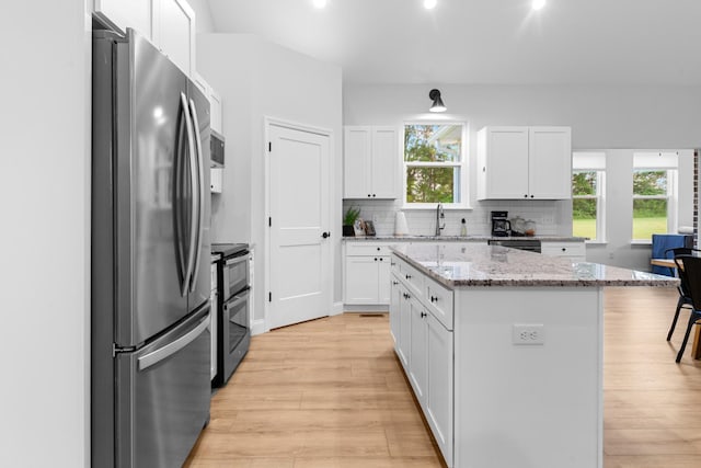 5283 Eagleville Pike, Eagleville, TN 37060 - kitchen featuring appliances with stainless steel finishes, a center island, light wood-style floors, decorative backsplash, and white cabinets