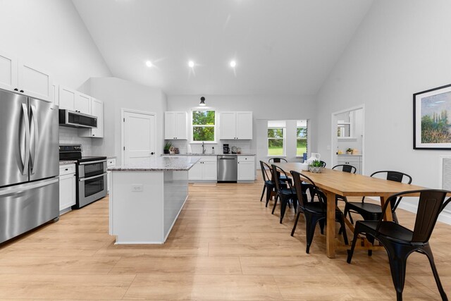 5283 Eagleville Pike, Eagleville, TN 37060 - kitchen featuring stainless steel appliances, high vaulted ceiling, decorative backsplash, a kitchen island, and white cabinets