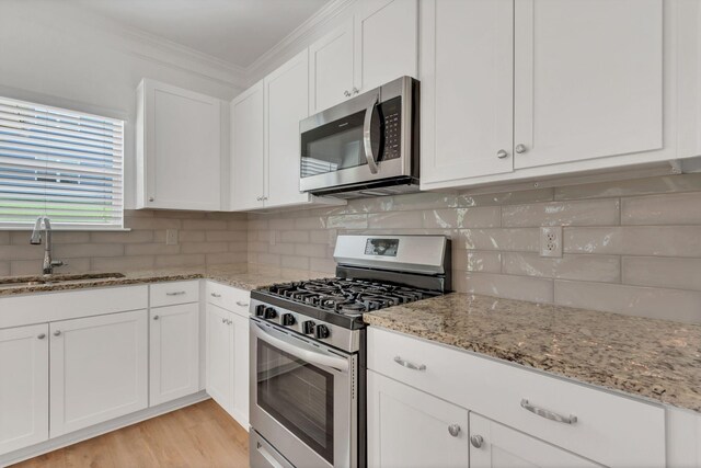 534 Morgan Meadows Way, Columbia, TN 38401 - kitchen featuring appliances with stainless steel finishes, white cabinetry, ornamental molding, light stone countertops, and backsplash
