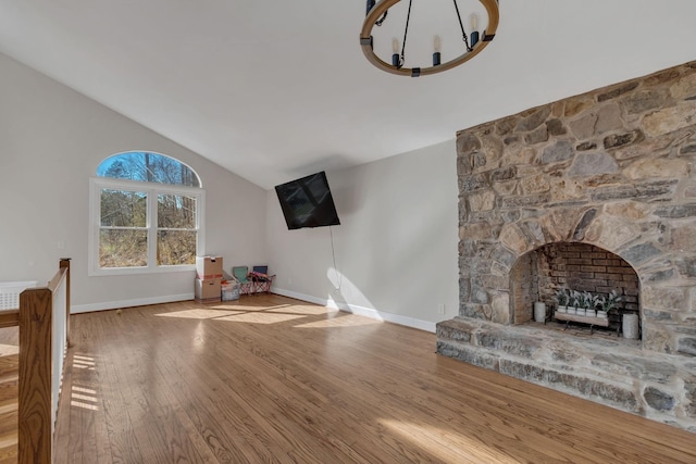 140 Carver Hollow Rd, Pleasant Shade, TN 37145 - unfurnished living room featuring wood finished floors, vaulted ceiling, a stone fireplace, and a chandelier