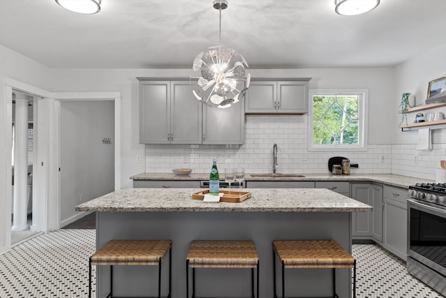 225 Hemphill Ave, Chattanooga, TN 37411 - kitchen with gray cabinets, stainless steel gas range, tasteful backsplash, and a kitchen breakfast bar