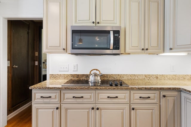 5033 Ragland Dr, Nashville, TN 37220 - kitchen with stainless steel microwave, cream cabinets, black electric stovetop, and light stone counters