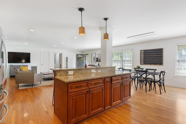 5033 Ragland Dr, Nashville, TN 37220 - kitchen with light wood-style flooring, light stone countertops, hanging light fixtures, brown cabinetry, and a kitchen island