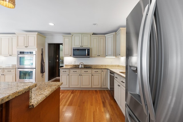 5033 Ragland Dr, Nashville, TN 37220 - kitchen featuring appliances with stainless steel finishes, cream cabinets, light stone countertops, light wood-style floors, and recessed lighting