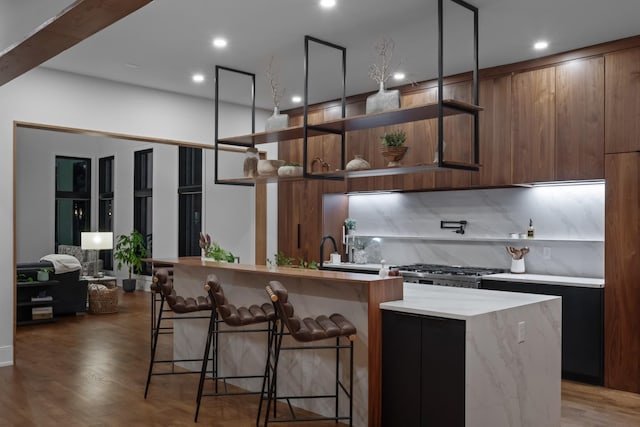 3706 Benham Ave, Nashville, TN 37215 - kitchen with modern cabinets, tasteful backsplash, an island with sink, a breakfast bar, and wood finished floors