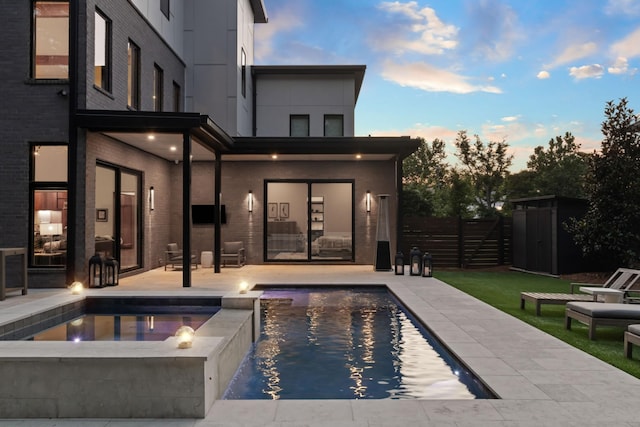 3706 Benham Ave, Nashville, TN 37215 - pool at dusk featuring a patio, a pool with connected hot tub, and an outdoor structure