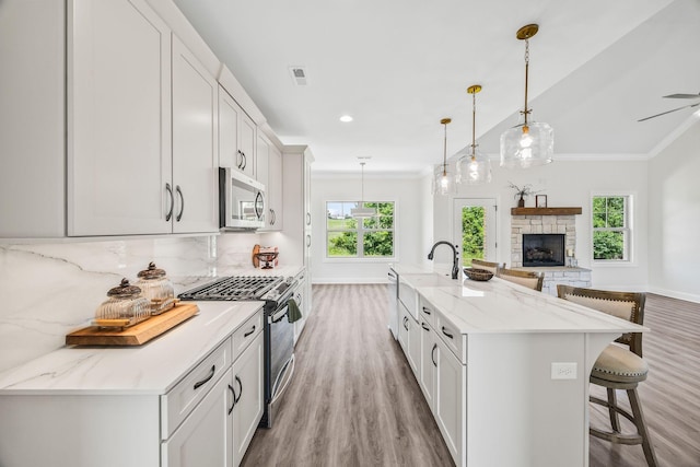 200 Creekside Dr, Lewisburg, TN 37091 - kitchen with stainless steel appliances, light wood-style floors, crown molding, a breakfast bar area, and a stone fireplace