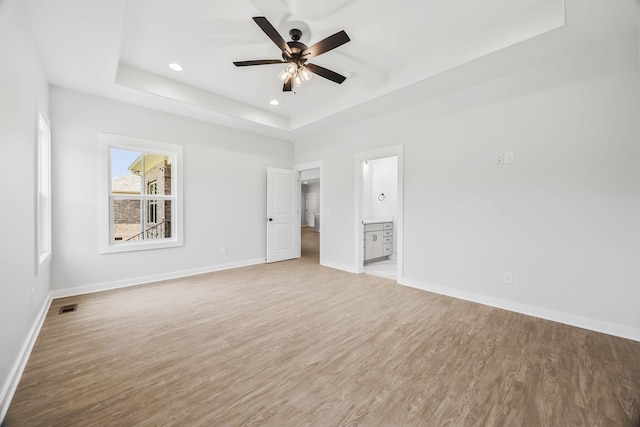 198 Creekside Dr, Lewisburg, TN 37091 - unfurnished bedroom featuring a tray ceiling, light wood-style floors, recessed lighting, ensuite bathroom, and ceiling fan