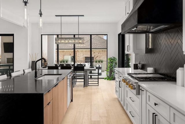 3037 Lakeshore Dr, Old Hickory, TN 37138 - kitchen with wall chimney exhaust hood, a chandelier, stainless steel appliances, light wood finished floors, and tasteful backsplash