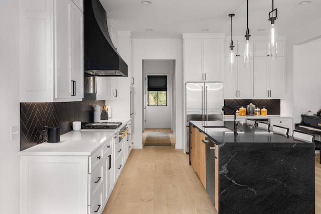 3037 Lakeshore Dr, Old Hickory, TN 37138 - kitchen featuring wall chimney range hood, appliances with stainless steel finishes, backsplash, light wood-type flooring, and a center island with sink