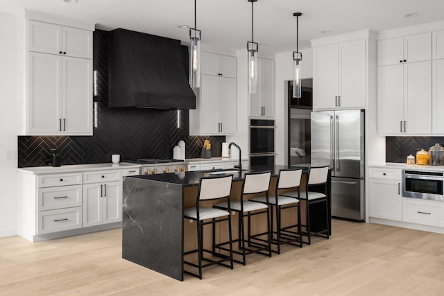 3037 Lakeshore Dr, Old Hickory, TN 37138 - kitchen featuring stainless steel appliances, exhaust hood, backsplash, an island with sink, and light wood finished floors