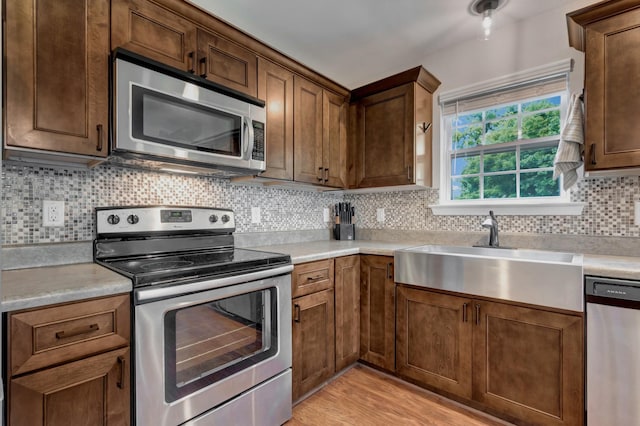 200 Woodsong Ln, Columbia, TN 38401 - kitchen featuring stainless steel appliances, light countertops, light wood finished floors, and decorative backsplash