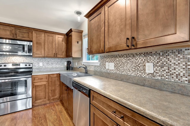 200 Woodsong Ln, Columbia, TN 38401 - kitchen with stainless steel appliances, light wood-style floors, backsplash, and brown cabinets