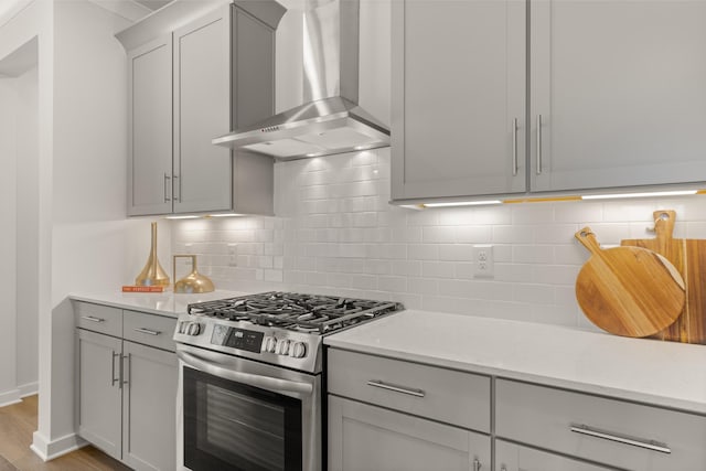 2453 Williams Ridge Dr, Columbia, TN 38401 - kitchen featuring stainless steel gas range oven, wall chimney range hood, gray cabinetry, decorative backsplash, and light wood-style floors
