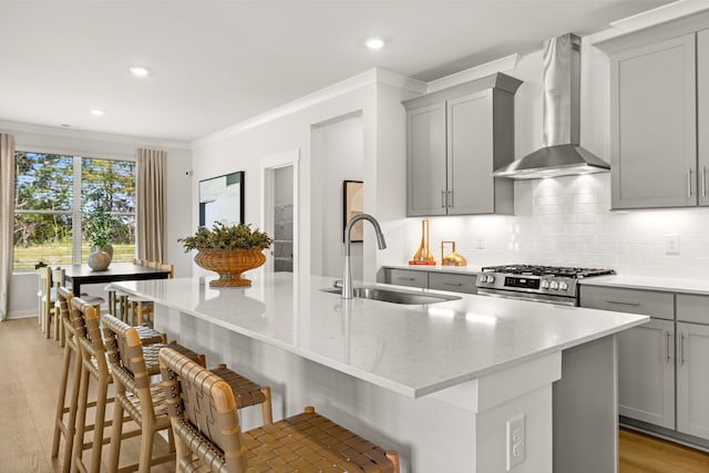 2453 Williams Ridge Dr, Columbia, TN 38401 - kitchen featuring wall chimney exhaust hood, gray cabinets, stainless steel range with gas cooktop, decorative backsplash, and a center island with sink