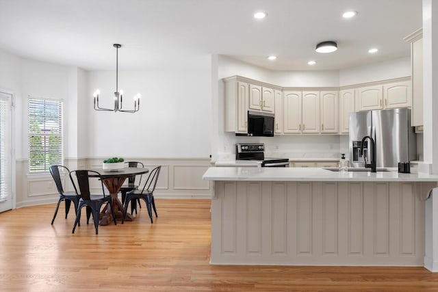9401 Lazy Circles Dr, Ooltewah, TN 37363 - kitchen with stainless steel appliances, light countertops, a wainscoted wall, a chandelier, and light wood-style flooring