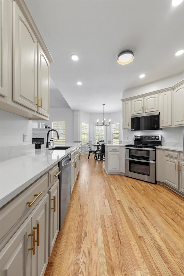 9401 Lazy Circles Dr, Ooltewah, TN 37363 - kitchen with stainless steel appliances, light wood-style floors, light countertops, recessed lighting, and a chandelier